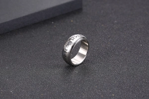Macro shot of silver titanium ring featuring deep engraved Nordic runes on a black surface
