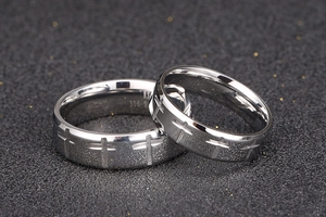 Macro shot of 316L stainless steel couple rings with engraved cross patterns