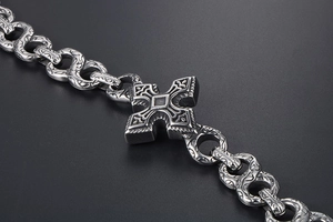 Macro detail of punk gothic stainless steel cross bracelet with ornate floral engravings