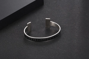 Detail of Viking Rune engravings on a matte silver stainless steel C-shaped cuff bracelet