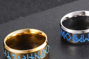 Dettaglio macro di anelli in titanio oro e argento con rune incise in blu