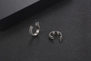 Detailed view of silver C-shaped titanium steel earrings with textured bead pattern