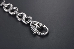 Detailed macro of a vintage silver punk bracelet with engraved cross and floral patterns
