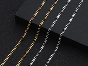 Close-up of gold and silver flat Cuban link chains on a textured black background