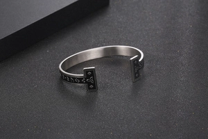 Detailed view of Viking runes and triquetra symbols on a brushed silver C-shaped cuff bracelet
