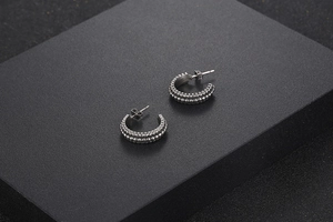 Detail of silver C-shaped titanium earrings with vintage double-row beaded texture