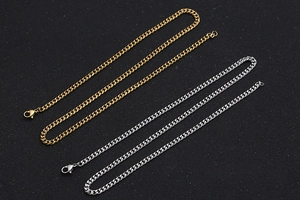 Detailed view of silver and gold cuban link chains with lobster clasp on black texture