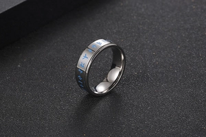 Macro view of polished titanium ring with blue Nordic Runic symbols on a black surface