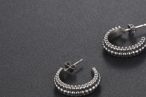 Macro detail of retro C-shaped titanium steel earrings with double-row beaded texture