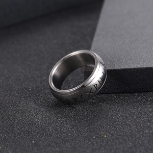 Titanium steel ring with engraved Nordic Viking runes on a textured brushed metal surface