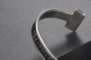 Macro detail of Viking rune engravings on a brushed stainless steel C-shaped cuff bracelet