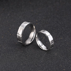 Polished titanium steel couple rings with engraved cross pattern on black background