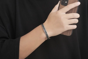 Close-up of silver Viking rune cuff bracelet worn by male model holding wood case phone