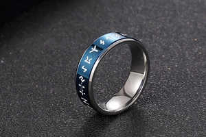 Macro detail of men's titanium steel ring with blue Nordic runes and silver polished edges