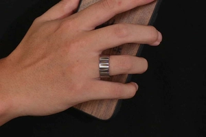 Close-up of titanium steel ring with vertical grooved texture on hand