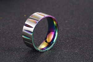Close-up of wide titanium ring with brushed metal surface and rainbow electroplated grooves