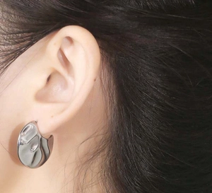 Detailed close-up of silver irregular fan-shaped earrings with high-polished texture