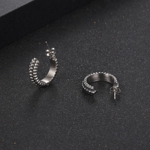 Retro C-shape titanium steel stud earrings with beaded texture on black surface