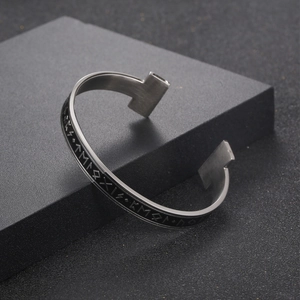 Men's silver Viking rune open cuff bracelet with black inlay on a dark pedestal
