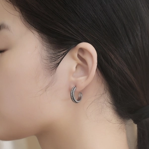 Vintage titanium steel C-shape hoop earrings with beaded texture on a female model