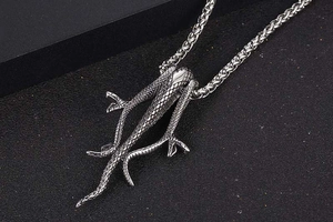 Macro detail of intertwined mamba snake pendant with textured silver scales and punk style
