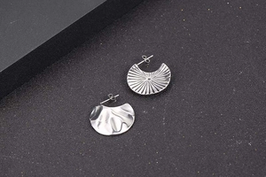 Detailed view of silver irregular fan-shaped earrings with pleated and hammered textures