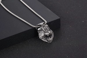 Detailed macro shot of vintage silver wolf and skull pendant on a black box chain