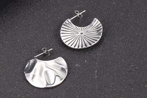 Detailed view of silver fan-shaped C earrings with sunray and fluid ripple textures