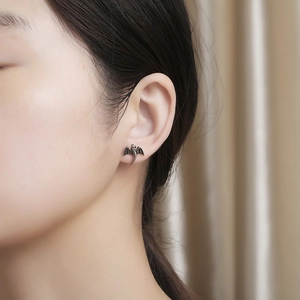 Gros plan d'une boucle d'oreille dragon en acier titane sur l'oreille d'un mannequin