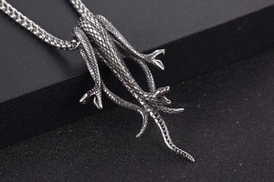 Macro shot of silver titanium steel Medusa pendant with detailed snake scales and texture