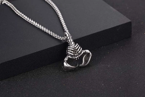 Macro detail of vintage stainless steel scorpion pendant with intricate carving on black stone
