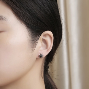 Close-up of vintage sunflower stud earring with black zircon on ear for women
