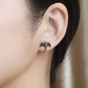 Gros plan d'une boucle d'oreille en forme d'aile de dragon argenté sur un mannequin