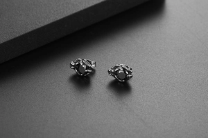 Macro detail of gothic claw stud earrings featuring a faceted round black stone in silver steel