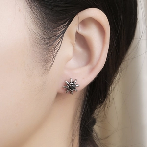 Detailed close-up of a vintage sunburst zircon stud earring worn on the earlobe