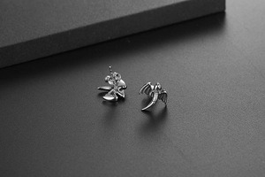 Détail de boucles d'oreilles dragon en argent avec ailes ciselées sur fond texturé