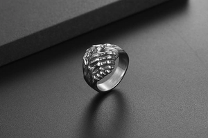 Détail macro de mains de squelette punk rétro s'enlaçant sur une bague en acier