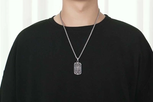 Detailed close-up of a vintage dragon relief pendant with silver wheat chain on a male model