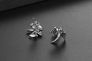 Détails macro de boucles d'oreilles ailes de dragon argentées avec fermoirs papillon