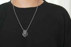 Detail of vintage wolf head pendant on a male model with realistic steel texture
