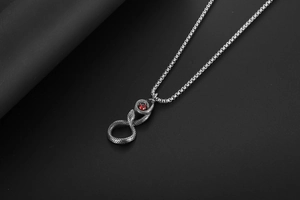 Détail macro du pendentif serpent rétro avec écailles et cristal rouge sur chaîne acier
