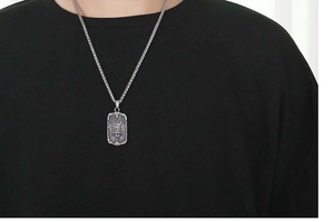Detail of silver dragon claw shield pendant on thick chain over black t-shirt