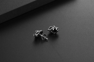 Close-up of black zircon stud earrings in silver steel setting with butterfly backs