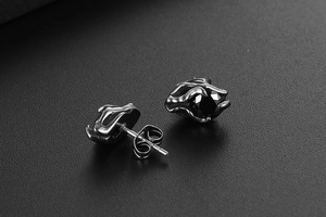 Macro shot of titanium steel stud earrings with faceted black zircon and vintage texture