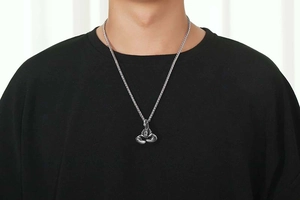 Detail of men's silver boxing glove pendant on thick woven chain worn by male model