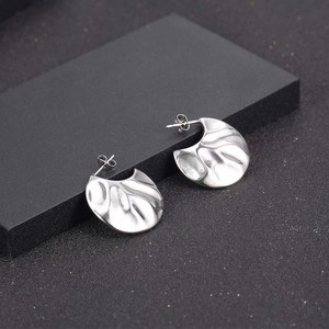 Modern irregular fan-shaped silver earrings in stainless steel with a wavy texture