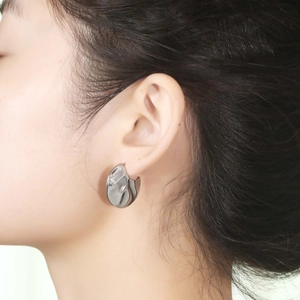 Irregular textured silver C-shaped fan earrings with a polished lava-style finish
