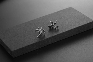 Détail macro de boucles d'oreilles ailes de dragon gothiques en argent sur support