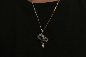 Close-up of vintage dragon pendant with snake-like scales and two-tone silver gold chain