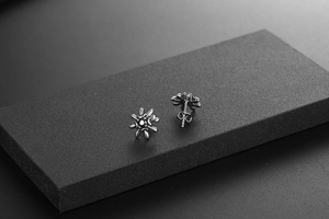 Macro view of vintage oxidized black titanium flower earrings with starburst petal details